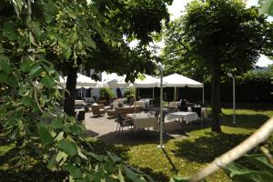 un patio con mesas, sillas y sombrillas blancas en Auberge de la Croix Blanche en Villarepos