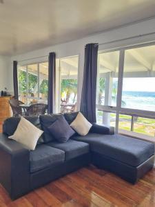 a blue couch in a living room with a view of the ocean at Ocean Beach Bach Rarotonga in Rarotonga