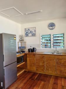 a kitchen with a stainless steel refrigerator and wooden cabinets at Ocean Beach Bach Rarotonga in Rarotonga