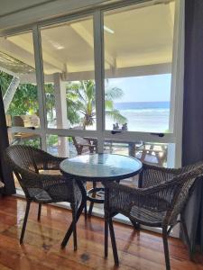 a table and chairs in a room with a view of the ocean at Ocean Beach Bach Rarotonga in Rarotonga +2 photos