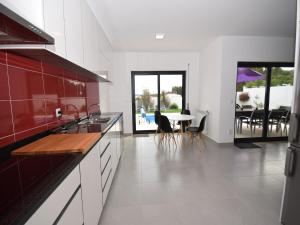 una cocina con armarios rojos y una mesa con sillas. en Holiday Home Nazaré Beach for Surfing, en Famalicão