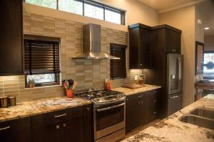 a kitchen with black cabinets and a stove top oven at Gleneagles Golf Course Retreat With Hot Tub in Columbia Falls +28 photos