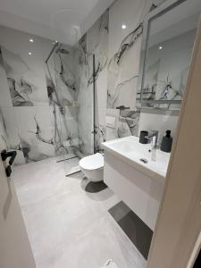 a white bathroom with a toilet and a sink at Vila Serenita in Vlorë