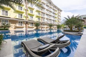 una piscina di un hotel con due sedie a sdraio di fronte a un edificio di Stylish Condo Near Airport- Poolview Amani Grand a Mactan Cebu International