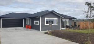 WaiotahiにあるWaiotahi Beach Houseの庭に私道がある小さな灰色の家