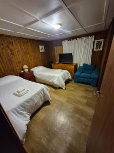 a hotel room with two beds and a blue chair at Casa completa para 5 personas. in San Carlos de Bariloche