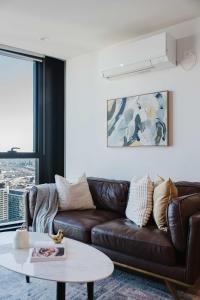 a living room with a brown leather couch and a table at Melbourne Modern CBD Stay Walk to Shops & Trams in Melbourne +47 photos