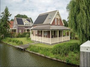 a house with solar panels on it next to a river at Bungalow by Water with Sauna in South Holland in Simonshaven