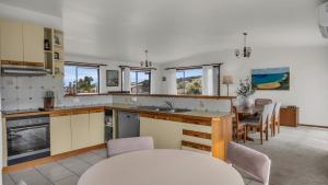 a kitchen and dining room with a table and chairs at Tura Beach Capes View House in Tura Beach