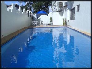 a blue swimming pool with a table and an umbrella at Buena Casa Hotel in Olongapo