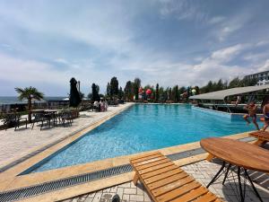 a large swimming pool with wooden chairs and tables at Ambassador Cottage in Korumdy