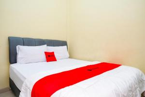 a bed with a red blanket on top of it at RedDoorz at Kutisari 2 Surabaya in Surabaya
