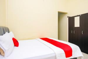 a bedroom with a white bed with red accents at RedDoorz at Kutisari 2 Surabaya in Surabaya