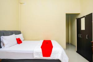 a bedroom with a bed with a red blanket on it at RedDoorz at Kutisari 2 Surabaya in Surabaya
