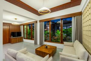 a living room with white furniture and large windows at The Bulih Ubud in Ubud