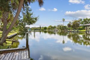 Un río con una pasarela de madera y palmeras. en 111 Sunset Drive, en Cocoa Beach