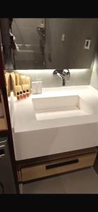 ein weißes Waschbecken in einem Badezimmer mit einem Spiegel in der Unterkunft Sea Breeze Polo Residences - One bedroom apartment in Nardaran