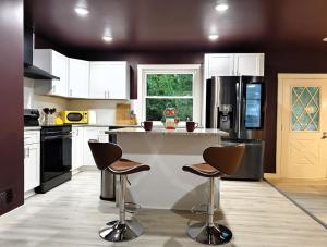 eine Küche mit weißen Schränken und einer Theke mit Stühlen in der Unterkunft Regal Ranch Retreat in Lawrenceville