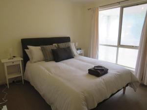 a bed with a black bag sitting on top of it at Blue Bird Cottage in Merrijig