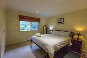 a bedroom with a large bed and a window at Sawmill Retreat in Merrijig