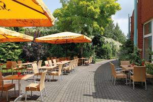 an outdoor patio with tables and chairs and umbrellas at Sunday Hotel Köln Hürth in Hürth