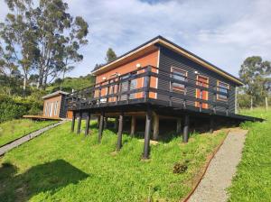 a large wooden house on a grassy field at Cabaña privada con acceso a playa in Castro