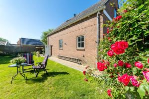a garden with a table and a bench and roses at Studio Wolken, Wind en Water. in Petten