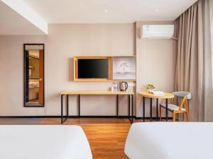 a room with two tables and a tv on the wall at JTOUR Inn Guigang Life Port High-speed Railway Station in Guigang