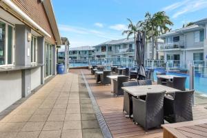 Un balcón con mesas y sillas y una piscina. en Pacific Blue Unit 175 Dual Swim Up, en Salamander Bay