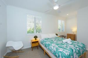 a bedroom with a bed and a chair and two windows at Yarrimbah Relaxed Coastal Getaway in Capel