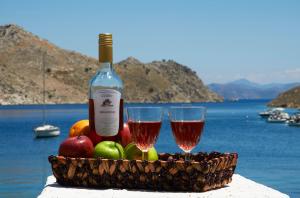 a basket of fruit and two glasses of wine at Kamares Studios in Symi