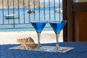 two glasses sitting on a table with a blue drink at Kamares Studios in Symi