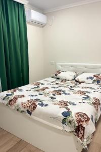 ein Schlafzimmer mit einem Bett mit geblümter Bettdecke in der Unterkunft Polo Guest House in Kobuleti + 13 Fotos