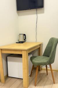 ein Holzschreibtisch mit einem grünen Stuhl und einem Fernseher in der Unterkunft Polo Guest House in Kobuleti