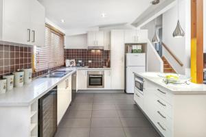 una cocina con armarios blancos y electrodomésticos blancos en Blackwood Chalet, en Merrijig