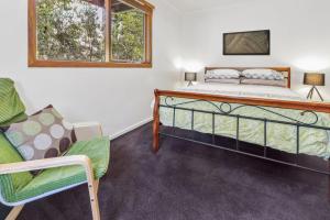 un dormitorio con una cama y una silla en Blackwood Chalet, en Merrijig