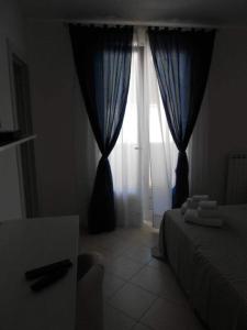 a bedroom with a bed and a window with blue curtains at B&B MA.RE. in Otranto