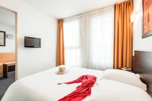 a hotel room with a bed with a red dress on it at Aparthotel Adagio Access Toulouse Jolimont in Toulouse
