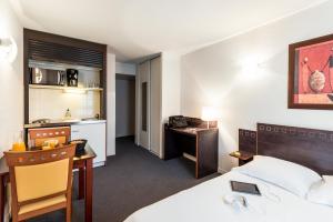 a hotel room with a bed and a desk and a kitchen at Aparthotel Adagio Access Toulouse Jolimont in Toulouse