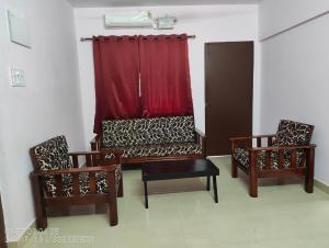 a room with two chairs and a red curtain at Pratheek in Udupi