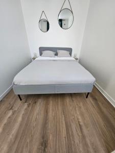 a bed in a white room with a wooden floor at Appartements Pavillons-sous-bois in Les Pavillons-sous-Bois