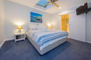 a bedroom with a large bed and a tv at Sea Renity On Earnshaw 3BR Beachside Bliss in Broadwater