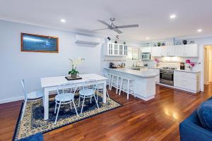 a kitchen with white cabinets and a table and chairs at Sea Renity On Earnshaw 3BR Beachside Bliss in Broadwater