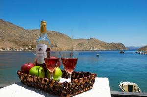 a basket of fruit and two glasses of wine at Kamares Studios in Symi