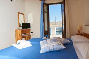 a bedroom with two beds and a television and a window at Kamares Studios in Symi
