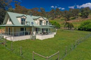 una casa con techo verde en un campo en Balewood House, en Bonnie Doon