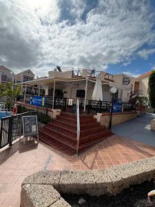 a building with stairs and an umbrella next to a pool at Costa Adeje Fañabé Beach in Adeje