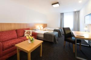 a hotel room with a red couch and a bed at Apartamenty Turek in Turek