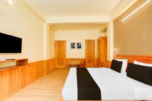 a hotel room with a bed and a flat screen tv at Hotel O Model Town Road in Manāli