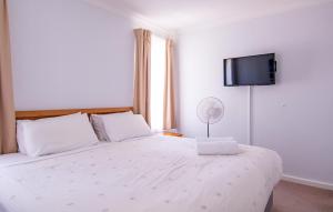 a bedroom with a white bed with a flat screen tv on the wall at Sea Breeze Family Retreat at Cape View Resort in Broadwater +28 photos